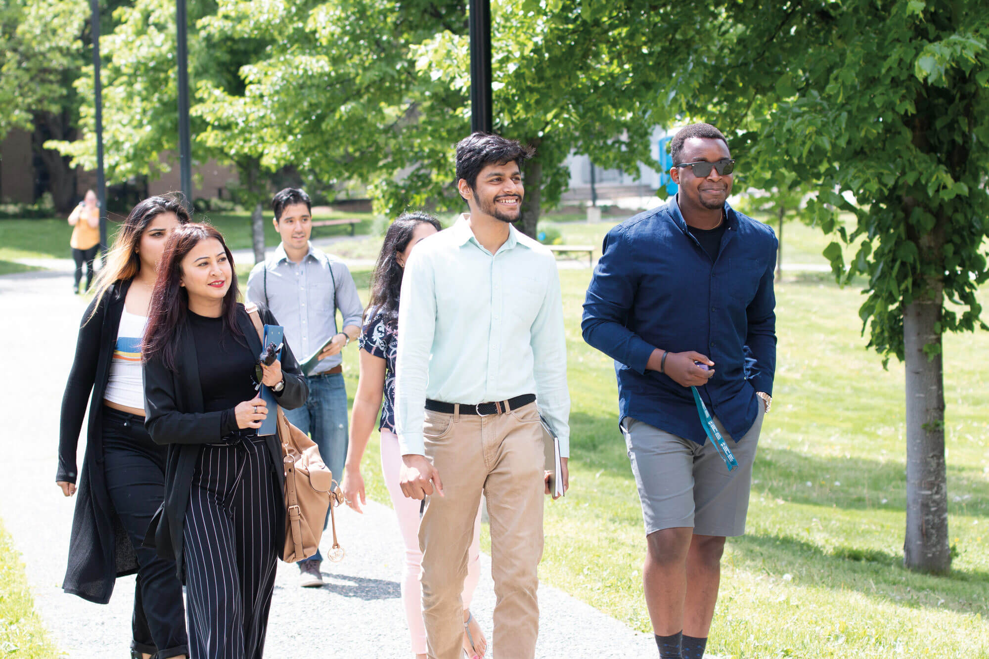 Diverse group of students walking through campus on a sunny summer day